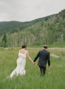 Ali & Jake walk hand in hand in the meadow of Beano's Cabin on their wedding day.